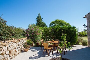 A patio with a table and chairs and a stone wall