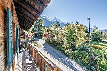 A view of a mountain from a balcony with blue shutters