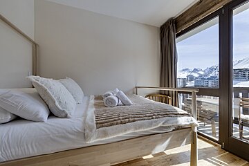 A bedroom with a bed and a window with mountains in the background