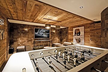 A room with a foosball table and a picture of a bear on the wall