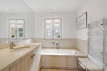 A bathroom with a tub a sink and a towel rack