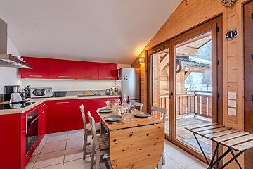 A kitchen with red cabinets and a wooden table