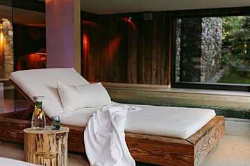A wooden lounge chair with a white blanket on it