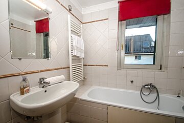A bathroom with a sink and a bathtub with a window