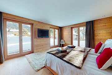 A bedroom with a large bed and a flat screen tv