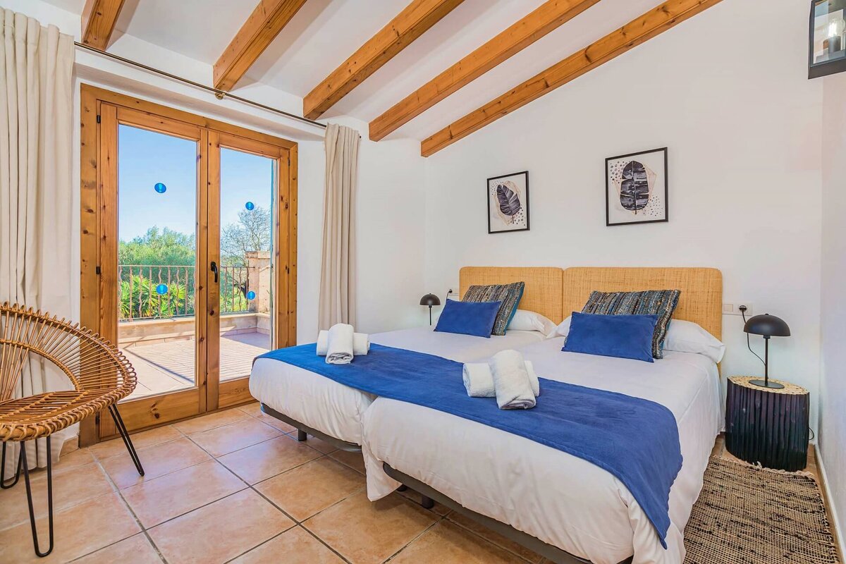 A bedroom with two beds and a wicker chair