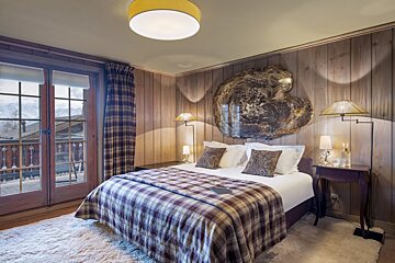 A bedroom with wood paneling and a bed with a plaid blanket
