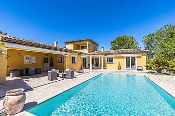 A yellow house with a large swimming pool in front of it