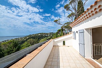 A balcony with a view of the ocean and trees