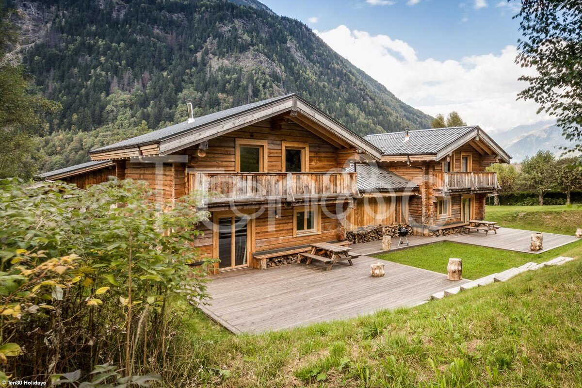 A picture of a log cabin with a mountain in the background