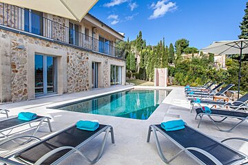 A large swimming pool is surrounded by lounge chairs and umbrellas