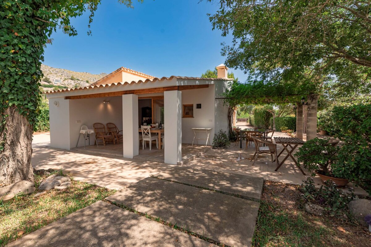 A white house with a covered patio with a table and chairs