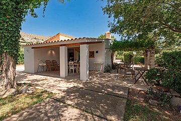 A white house with a covered patio with a table and chairs