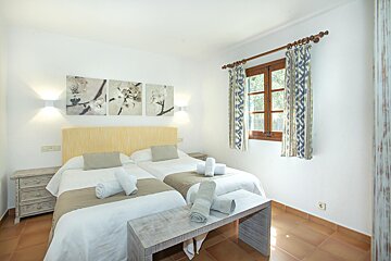 A bedroom with two beds and two paintings on the wall