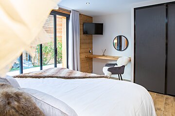 A bedroom with a bed a chair and a television