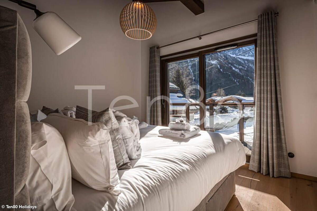 A bedroom with a bed and a window with the word ten80 on the bottom