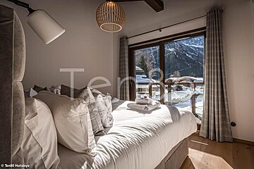 A bedroom with a bed and a window with the word ten80 on the bottom