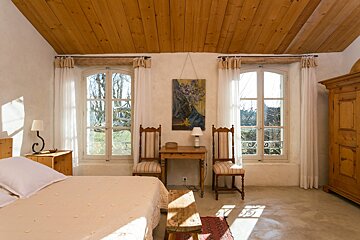 A bedroom with a painting on the wall above the bed