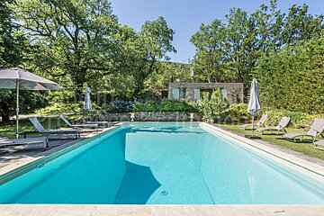 A large swimming pool is surrounded by chairs and umbrellas
