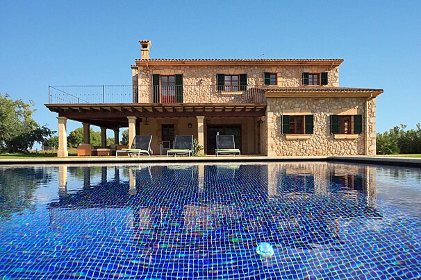 A large stone house with a swimming pool in front of it