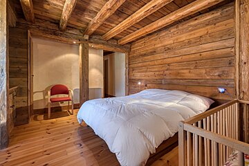 A wooden bedroom with a bed and a chair