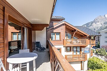 A balcony with a table and chairs in front of a building that has a sign on it that says