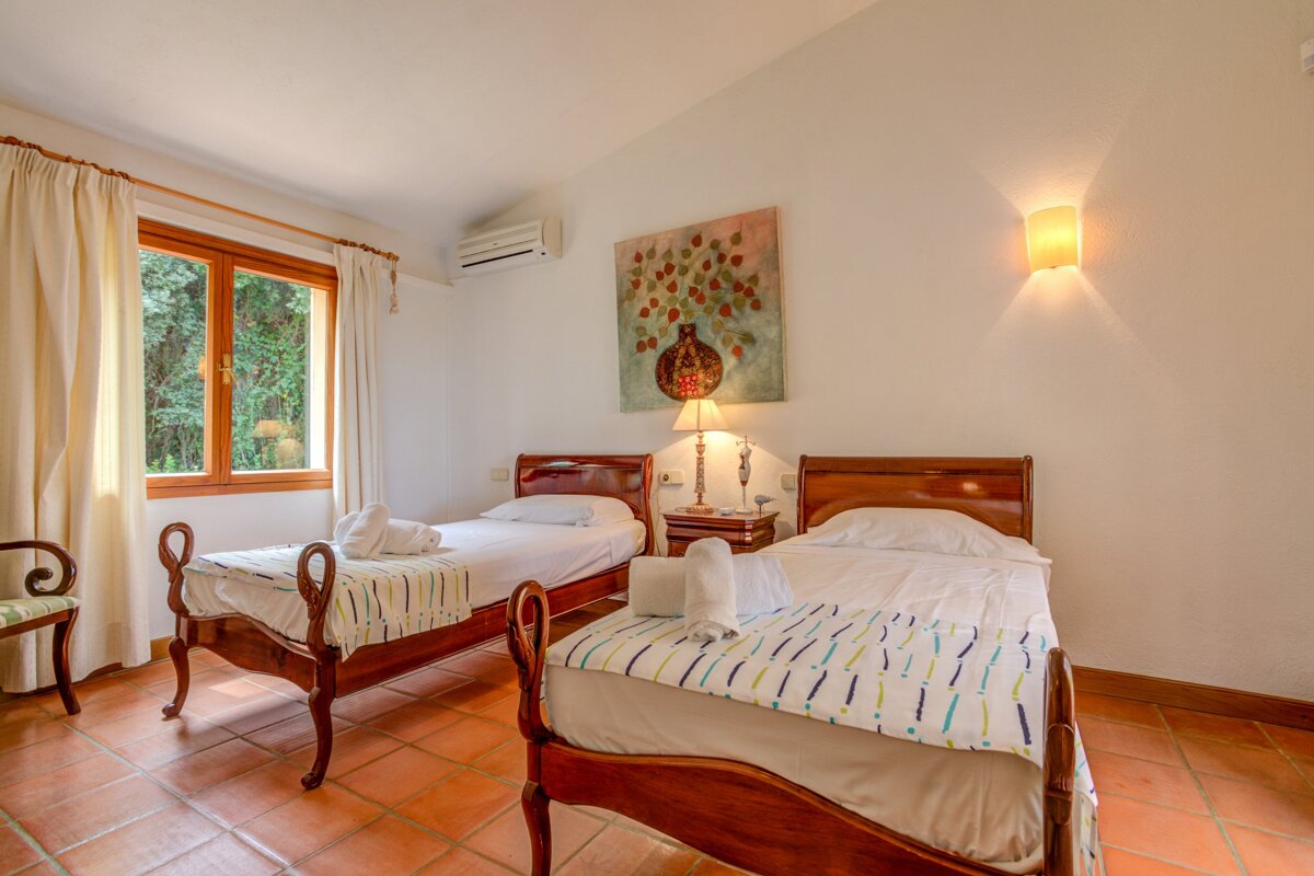 A bedroom with two beds and a painting on the wall