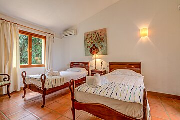 A bedroom with two beds and a painting on the wall