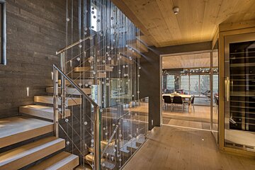 A staircase with a glass railing leading to a dining room
