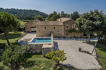 A large stone house with a swimming pool in front of it