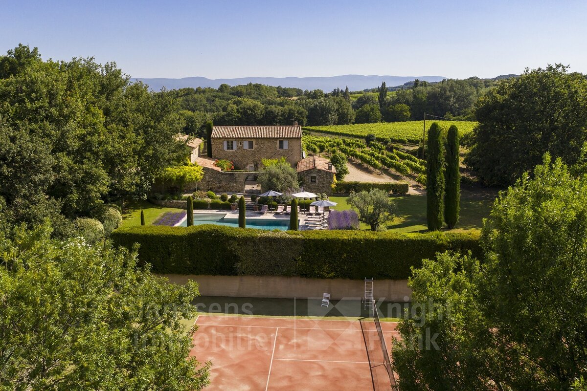 An aerial view of a house with a tennis court in front of it