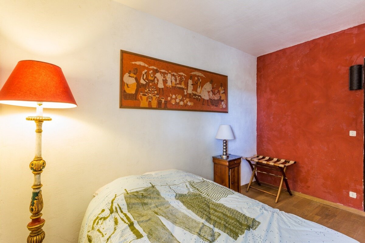 A bedroom with a lamp and a painting on the wall