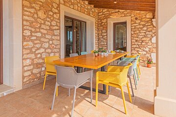 A patio with a table and chairs in front of a stone wall