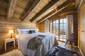 A bedroom with a large bed and a chair
