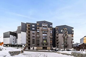 A large building with a bus parked in front of it in the snow