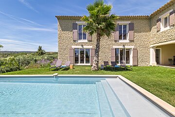 A large stone house with a swimming pool in front of it