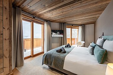 A bedroom with a large bed and a flat screen tv