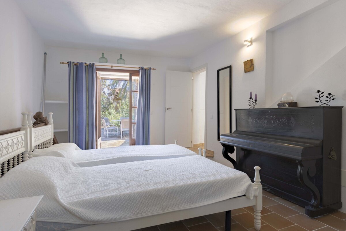 A bedroom with two beds and a piano in the corner
