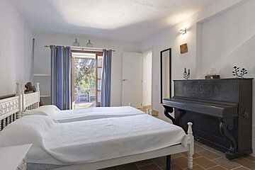 A bedroom with two beds and a piano in the corner