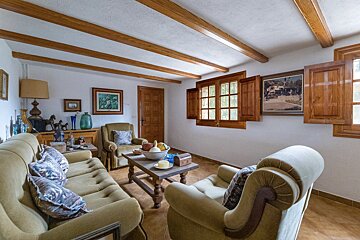 A living room with a couch and chairs and a painting on the wall