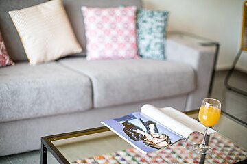 A magazine on a table next to a glass of orange juice