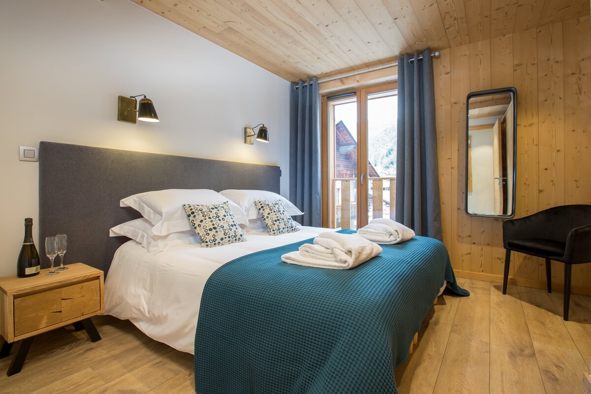 A bedroom with a large bed and a bottle of champagne on the nightstand