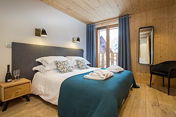 A bedroom with a large bed and a bottle of champagne on the nightstand