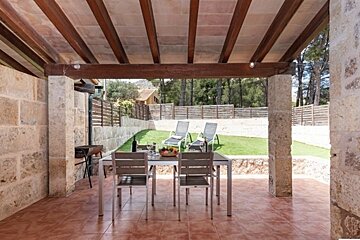 A patio with a table and chairs under a wooden roof
