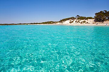 A large body of water with a sandy beach in the background