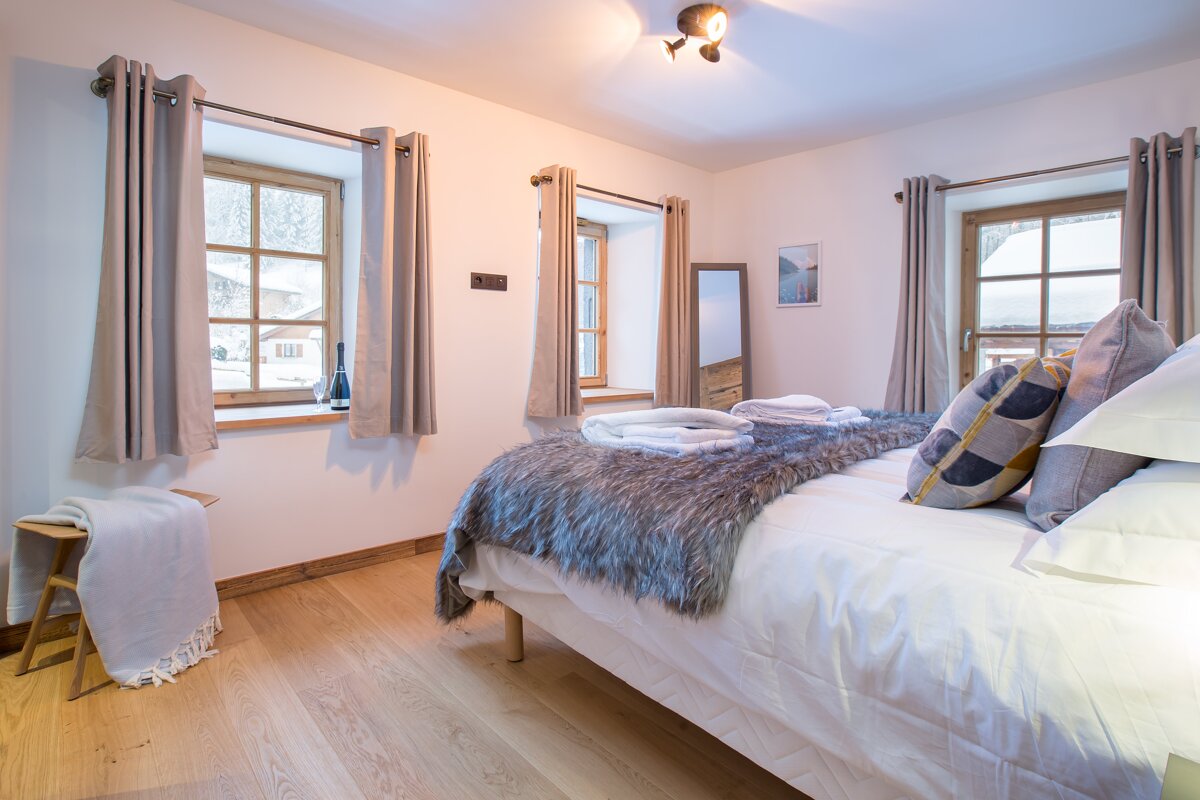 A bedroom with a bed and a window with a picture on the wall