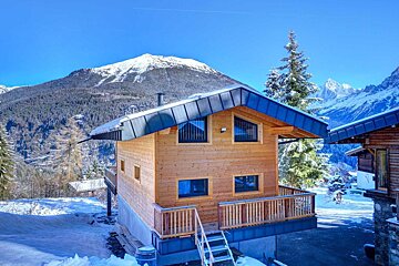A snowy mountain is behind a wooden house