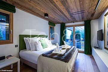 A bedroom with a wooden ceiling and green curtains