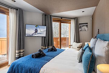 A bedroom with a large bed and a flat screen tv on the wall