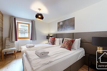 Cozy, well-lit bedroom featuring two beds with white linen and decorative pillows, a window, and dandelion artwork.